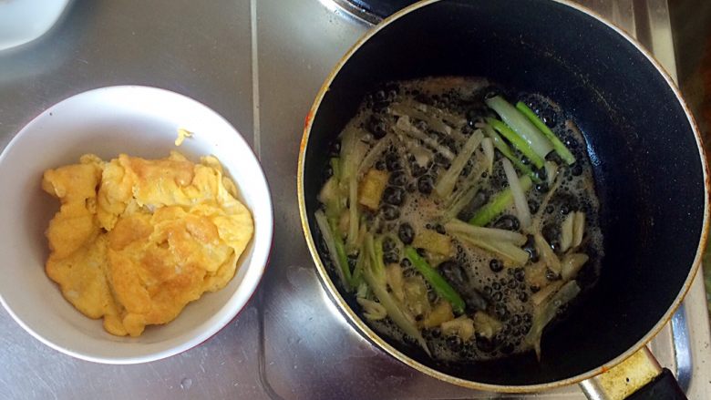 梅干菜炒意面,待鸡蛋两面金黄时,出锅。并倒入葱、姜、蒜。