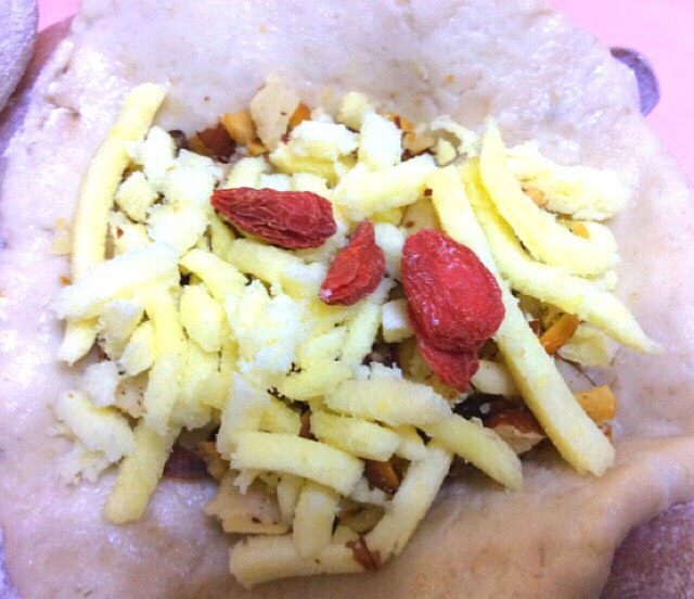 香蕉果仁糯米芝麻饼,在放一小勺芝士放几颗枸杞,收口压成饼