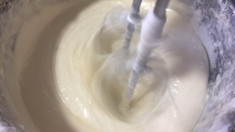 核桃蔓越莓牛轧糖(熬糖版),把黄油分两次倒入锅中,用打蛋器高速混匀