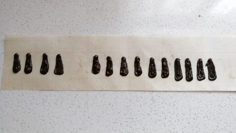 小狗纸杯蛋糕,然后将少许巧克力装入裱花袋隔热水溶化,溶化后裱花袋剪小口,在油纸或油布上挤出小狗耳朵形状然后把挤好的奶油用抹刀稍微抹平