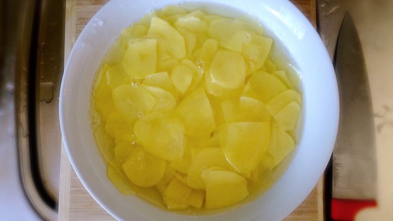 黑胡椒土豆玫瑰卷,准备一大碗淡盐水,将切好的土豆放入淡盐水中,洗去表面的淀粉。