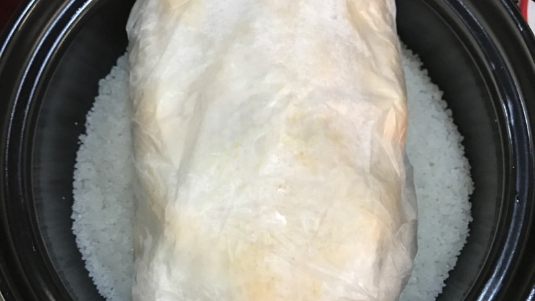 砂锅盐焗鸡,将炒好的海盐取出三分之二,另外的三分之一平铺在砂锅中,放入包裹好的鸡。
