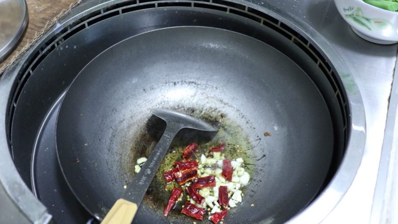 干煸四季豆,油锅烧热，放入干辣椒、蒜末，炒香。