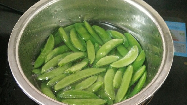 荷兰豆炒虾仁,盆里放水加入适量油和盐，烧开。放入荷兰豆烫一下，捞出。