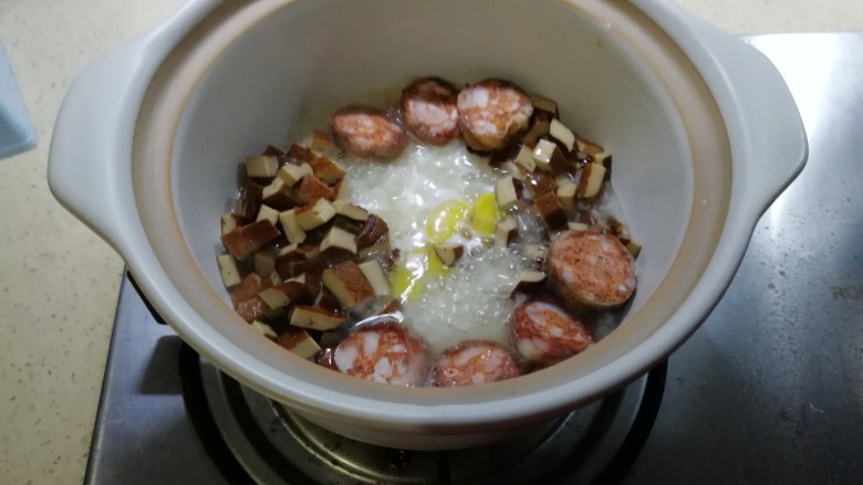 香肠煲仔饭,焖一下,水半干,铺上香肠,香干,盖上盖子继续焖