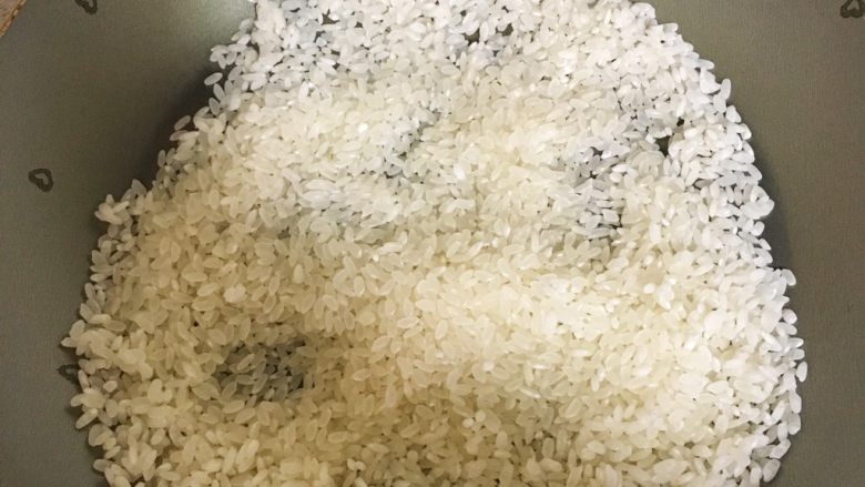 宝宝辅食6M➕:止泻焦米汤,将大米倒入锅中,再开小火翻炒