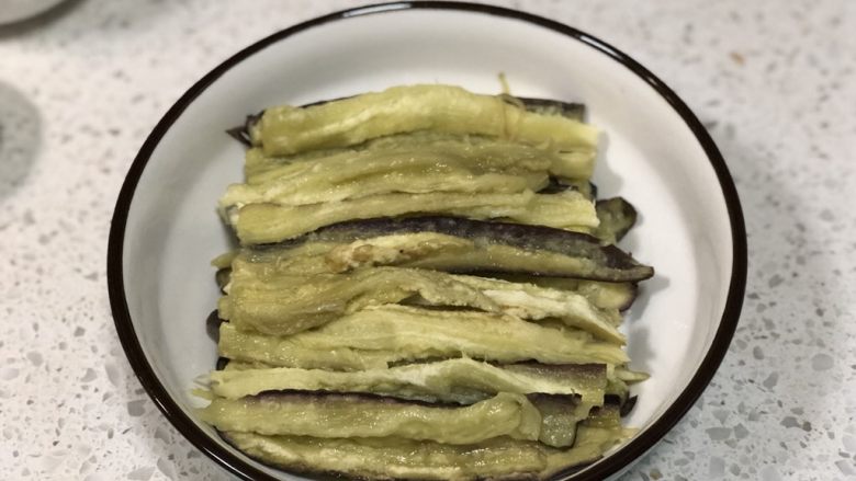 凉拌手撕茄子,取出蒸熟的茄子,放温热不烫手后先把每一半茄子对半切开,然后用手撕成小长条,摆放在盘子内