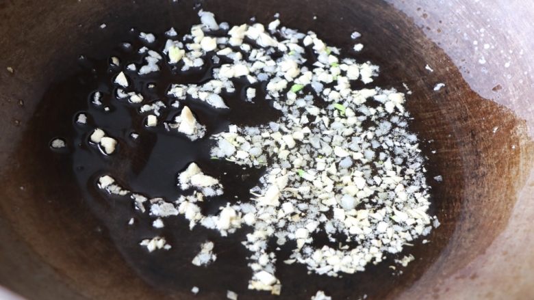 蒜苔炒腊肠,锅内放适量色拉油,放蒜末炒香;