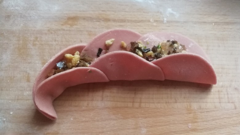 番茄素馅玫瑰蒸饺,再立起来,从左端开始向内卷起来,收尾处捏紧沾点水粘紧