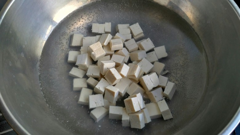 麻婆豆腐,起锅烧水,水开把豆腐放入煮一分钟。用开水焯豆腐可以去除豆腥味,也可以保持豆腐形状不易碎。