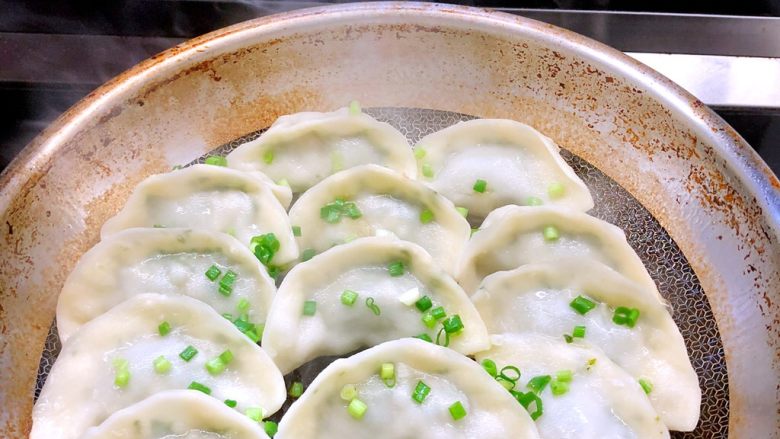 荠菜猪肉煎饺,打开锅盖，洒上葱花并盖上锅盖等20秒后关火。