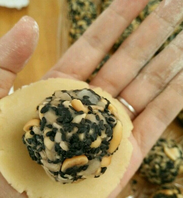 五仁馅月饼,拿一个饼皮用手掌稍微压扁,放上五仁馅。