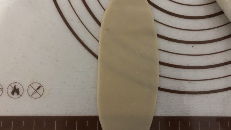 椒盐芝麻牛舌饼,取一个包好的面团,按扁,用擀面杖擀成椭圆,不要擀破,否则会露酥