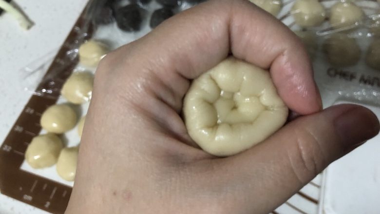 椒盐芝麻牛舌饼,取一个分好的油酥放在水油皮中间,用虎口慢慢收口