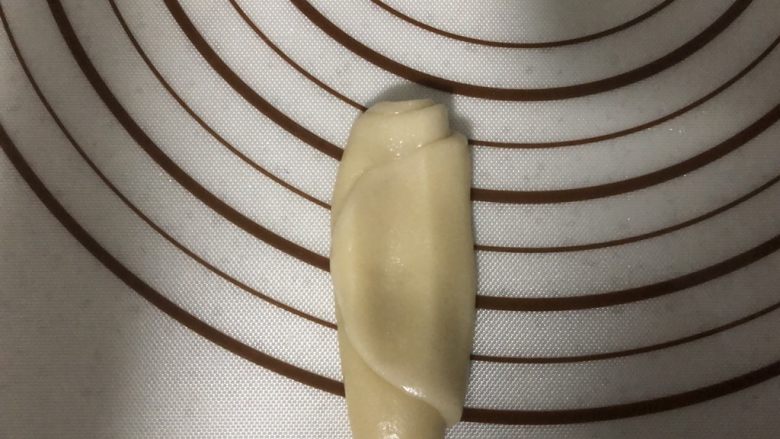 椒盐芝麻牛舌饼,静置好进行第二次擀卷,取一个面卷竖着收口朝上,放置,按扁
