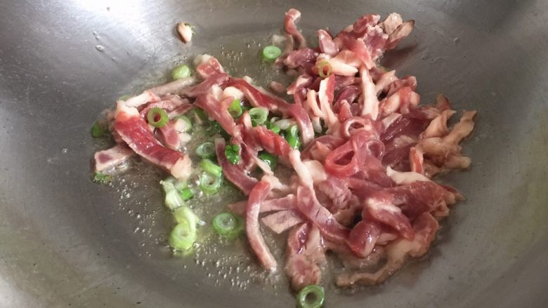 蒜苔炒肉,锅内放油烧热,放入葱碎和肉丝翻炒片刻