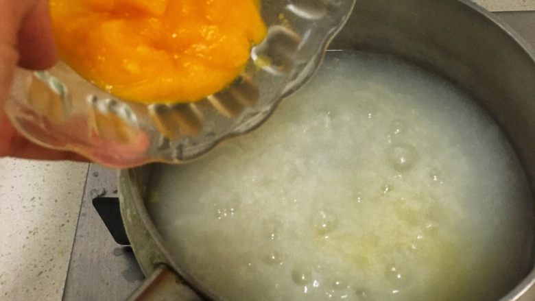 宝宝辅食8M➕:南瓜蛋黄十倍粥,此时大米粥已经基本上煮好,将南瓜泥倒入粥中一起煮