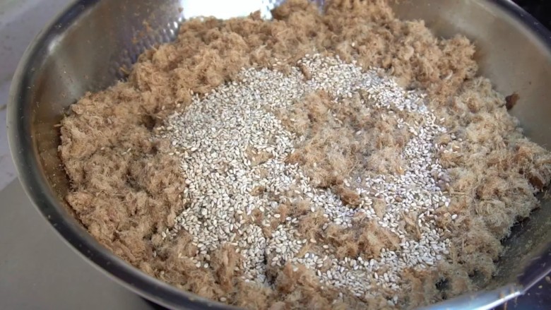 自制肉松,打成蓉的肉松再倒回平底锅里,最小火翻炒到肉松完全干燥,加入烤香的白芝麻