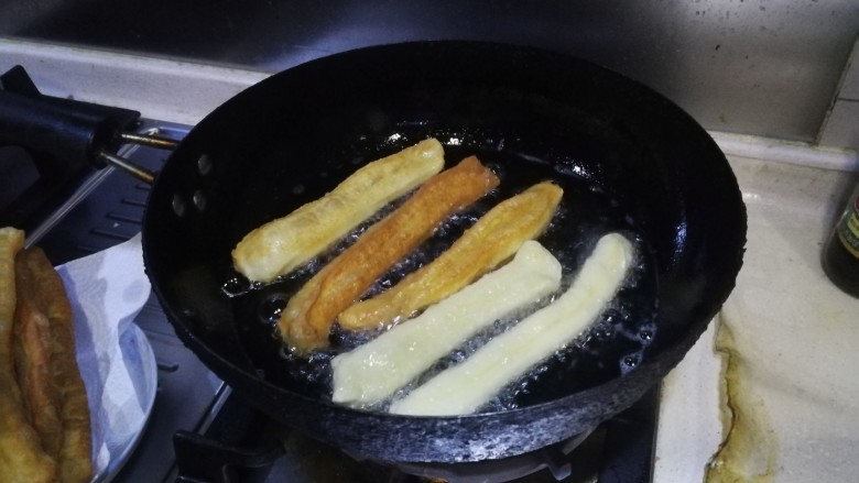 自制安心油条,大锅加入适量玉米油,大火将油温烧至筷子戳进去起大泡,然后将做好的油条生坯放入油锅炸制,两面金黄捞出即可