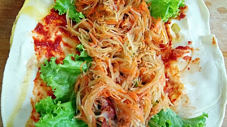 鸡蛋灌饼,再铺上炒好的醋溜土豆丝和胡萝卜丝。卷起来,切开就好。(饼小的话就不用切了,我这个饼比较大,我就切了一下。)