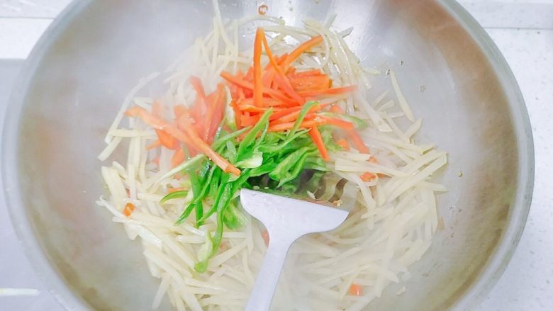 红黄绿&酸辣土豆丝,土豆丝炒到半透明的时候,加入辣椒丝,翻炒。