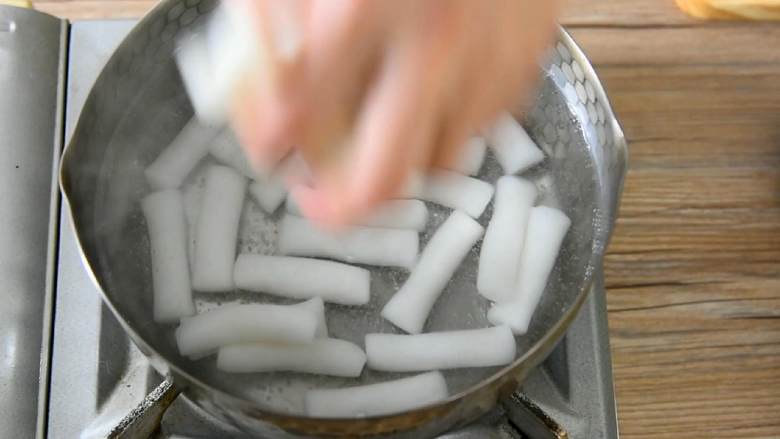 不寻常的年糕做法:辣白菜炒年糕,让你唇齿留香!,水冒气泡时下年糕,大火煮约2分钟后捞出。