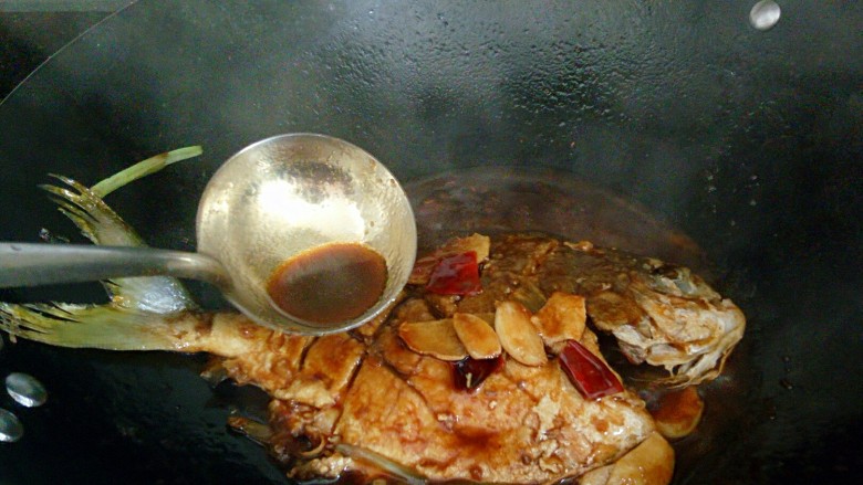 秘制红烧鲳鱼,用勺子舀起汤汁不断浇到鱼身上,让鱼更入味