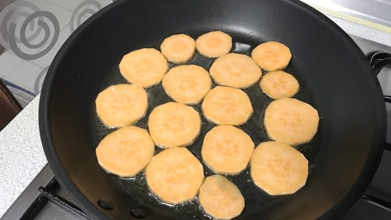 家常小零食~地瓜干儿,地瓜片平铺于油锅里。