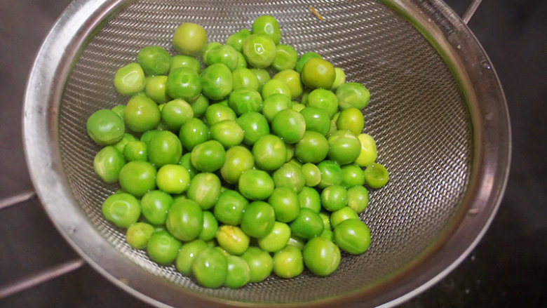 花甲豌豆,将煮熟的豌豆粒捞出沥干水分,然后放入冰水中,让豌豆保持翠绿的颜色
