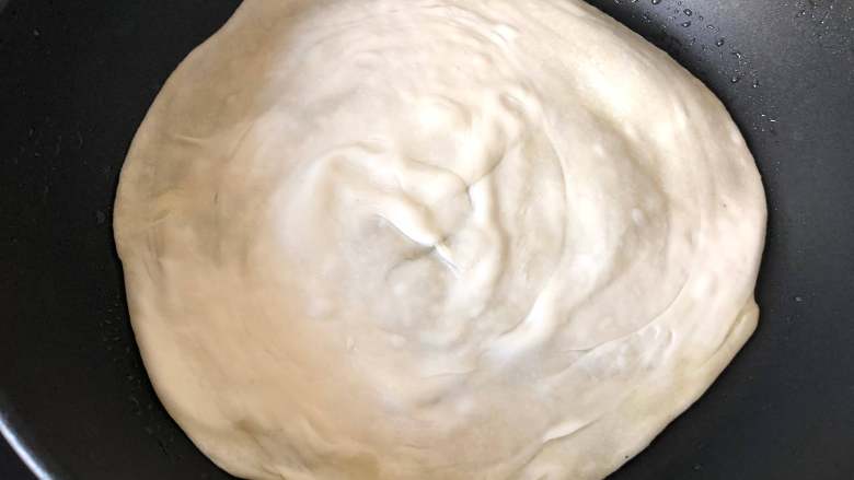 网红手抓饼,平底锅放少许油,将饼胚放入,小火煎至金黄色