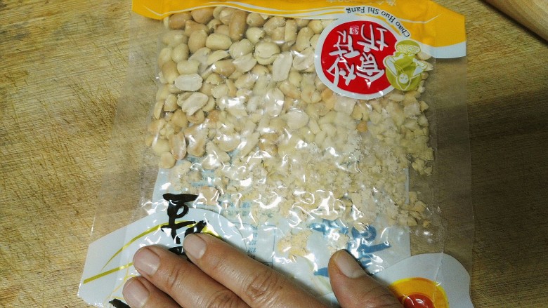 酸甜可口还香喷喷的牛轧糖,把花生衣去干净的花生重新倒进包装袋里,用擀面杖擀成碎。
