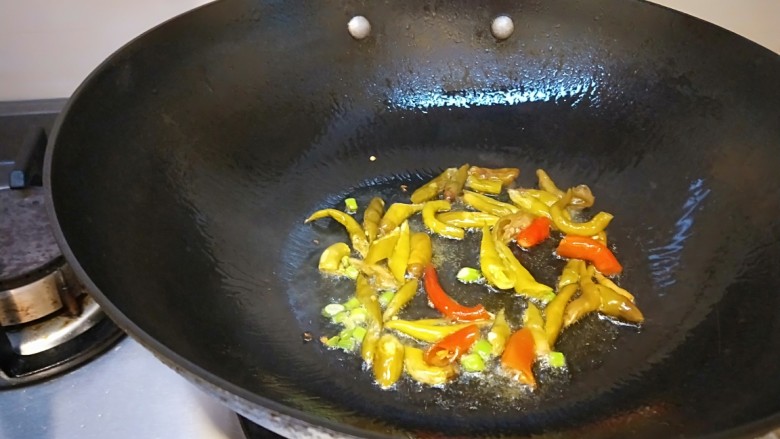 泡椒炒腊肉,锅中放适量油烧热,放入泡椒炒出香味。