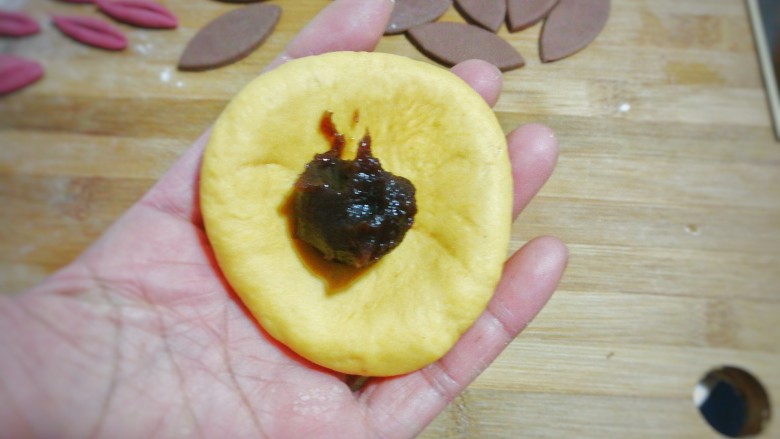 大黄狗豆沙包,取一个黄面团用擀面杖稍微擀开，再用手凹成窝形放入适量<a style='color:red;display:inline-block;' href='/shicai/ 4729'>豆沙馅</a>