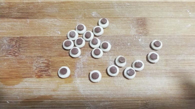 大黄狗豆沙包,再用镊子夹住可可小圆片，沾点水放在白圆片上面沾紧，这样大黄狗眼睛也做好了