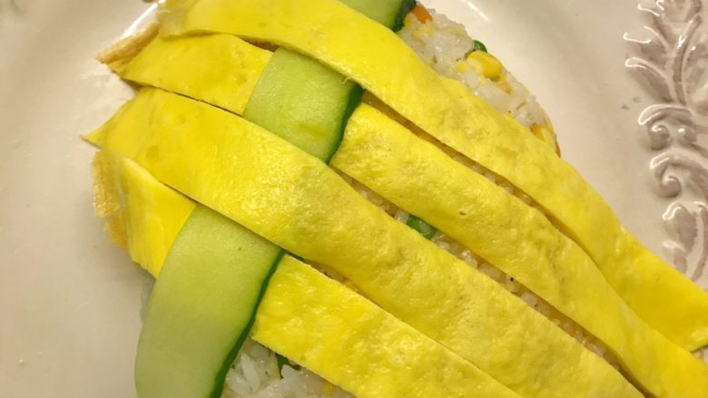 菠萝造型炒饭,黄瓜提前削片,将黄瓜片和鸡蛋皮相互编织