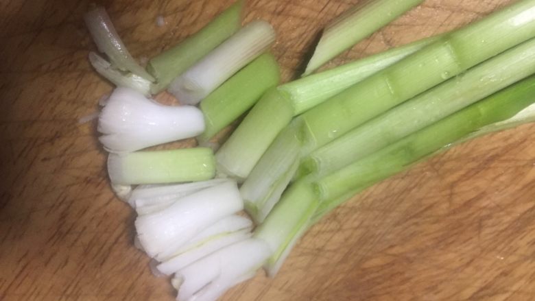 渝派回锅肉,先用刀拍把蒜苗头斜刀切段,切好的径和叶分开放备用