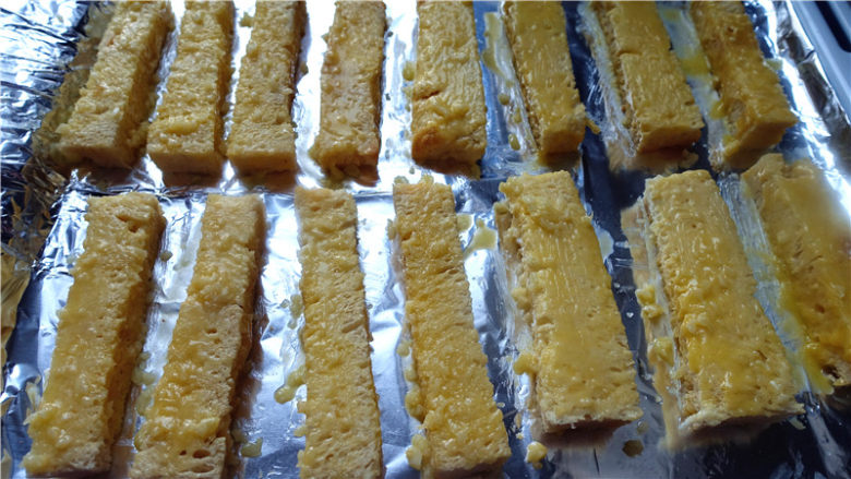 蒜香面包,取一个面包块,在其中一面抹上一层蒜蓉奶油。把抹了蒜蓉奶油的一面朝下放入烤盘,再用抹刀把其他几面都抹上蒜蓉奶油。