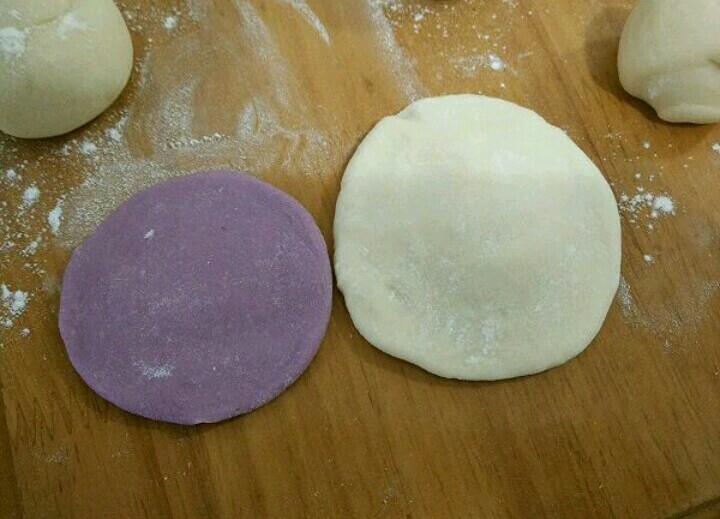 紫薯刺猬包子,取一个白色和紫色剂子,分别擀成中间厚的圆形。