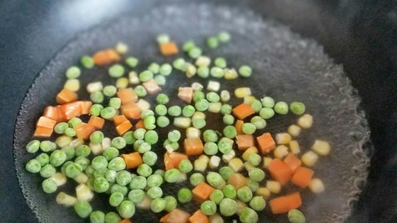 【快手下饭菜】豌豆炒鸡丁,锅中加入水大火烧开,下入豌豆,玉米粒,胡萝卜丁焯水,2分钟捞出淋干水份。
