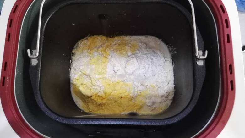 卷卷椰蓉包,面包机桶里,加入牛奶与酵母的混合液,加入面包粉、白糖、玉米粉,启动和面程序。