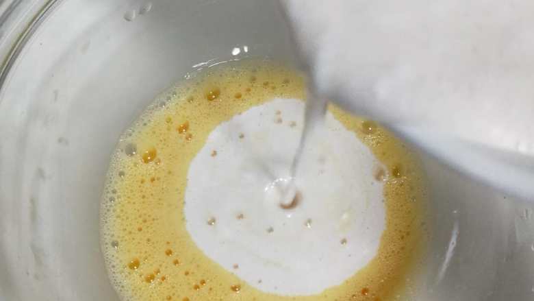 fluff金沙奶黄蛋挞酥,将步骤六中的奶液慢慢倒入打散的鸡蛋液中,辅助手动打蛋器边倒边搅拌,避免烫熟鸡蛋液。直到彻底混合以上液体。