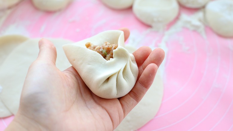 鲜肉包子(一次发酵法),左手托住底部,用右手拇指和食指沿着边缘捏出褶状