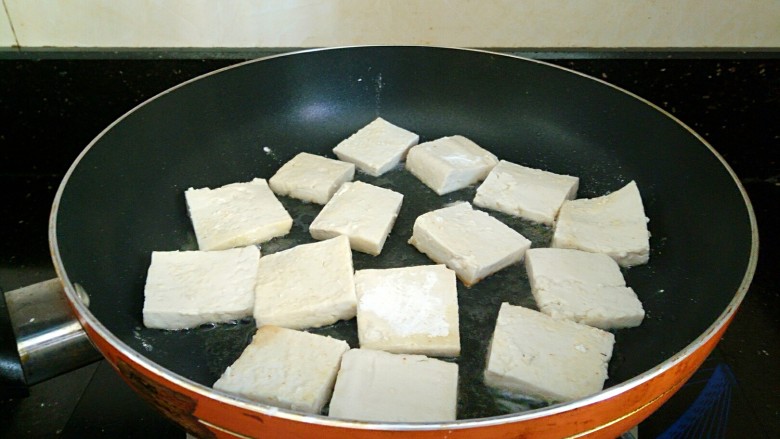 椒香脆皮豆腐,平底锅放适量油加热,豆腐码上,中火煎