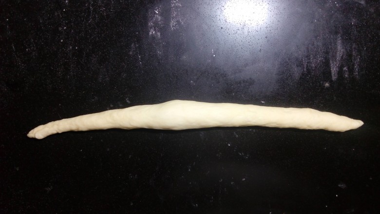 炼奶辫子面包,两手掌从中间往两端,慢慢搓长。