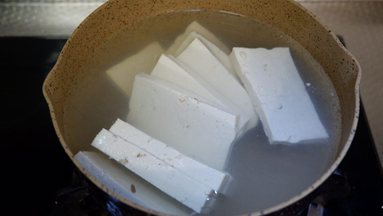 红白豆腐炖肉末,锅中烧开水,先将豆腐放入沸水中焯一下,捞出沥干水。