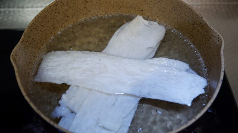培根杏鲍菇年轮卷,锅中烧开水,将杏鲍菇焯烫一下。不要火太大,微软能卷起来就可以。焯好捞出沥干水备用。