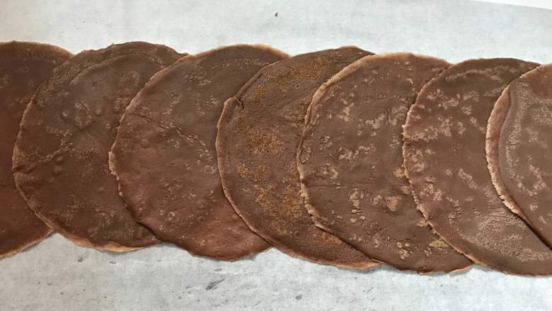 可可毛巾卷,取一张油纸,把晾好的饼皮一张叠一张放好。