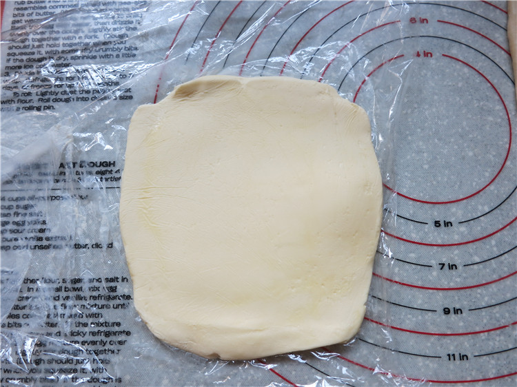 新网宠面包“白富美”净净包,将145克片状黄油包在保鲜膜里,先用擀面杖上下左右敲打几下,然后擀成正方形,大小正好可以包入面团中即可,擀好的黄油要与面团软硬度一致
