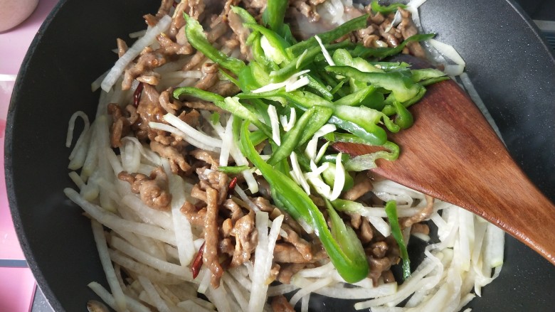 萝卜丝炒牛肉,放入青椒,大蒜翻炒。