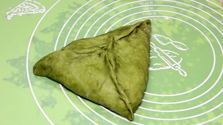 抹茶坚果软欧包,将二份面团擀开,小面团叠加上面,再翻过来搞成三角包,口子收紧。